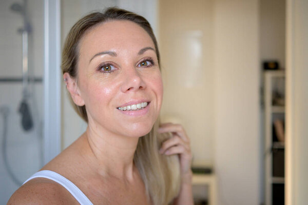 Довольно привлекательная женщина в ванной утром весело расчесывает волосы