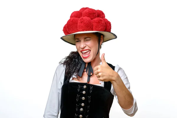 热情笑年轻黑森林女人穿着传统 Bollenhut 与红色彩色绒球 给予审批上白色孤立手势竖起大拇指 — 图库照片