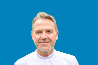 Çekici, orta yaşlı bir adamın portresi. 50 'li yaşlarda, mavi bir arka planda, nazik bir gülümsemeyle.