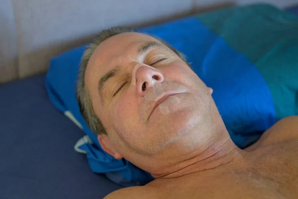 Śpiący Mężczyzna Średnim Wieku Taśmą Nosa Taśmą Ust Leżący Łóżku — Zdjęcie stockowe