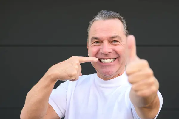 stock image Man with a big smile is pointing on his teeth because this made the best dentist in town