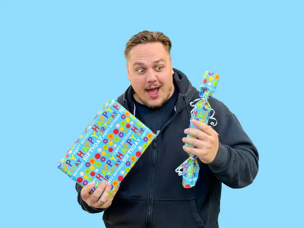 Astonished looking man holding two blue boxes with presents in them, in the style of candycore