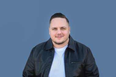 Siyah deri ceketli ve arkaya taranmış saçları olan 20 'li yaşlarda çekici genç bir adam kameraya cana yakın görünüyor.