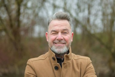 Gri saçlı ve gri sakallı orta yaşlı bir adamın portresi. 