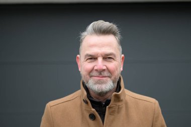 Gri saçlı ve gri sakallı orta yaşlı bir adamın portresi. 