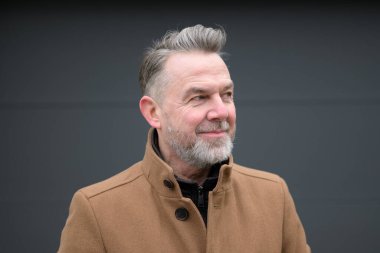 Gri saçlı ve gri sakallı orta yaşlı bir adamın portresi. 