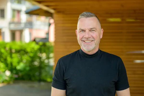 stock image A mature man with gray hair and a beard smiles warmly at the camera