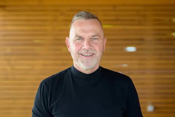 stock image A cheerful mature man with gray hair and a beard smiles warmly at the camera.