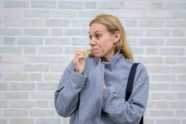 Gri paltolu sarışın bir kadın kurnaz ve bilgili bir gülümseme ile orta yüz ifadesinin ortasında yakalandı..