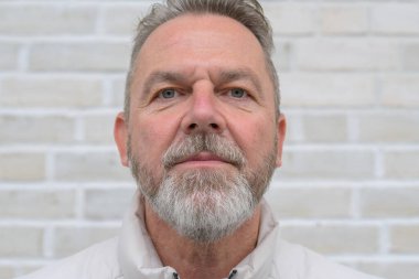 Gri sakallı ve sakallı olgun bir adamın resmi. Doğrudan kameraya bakıyor..