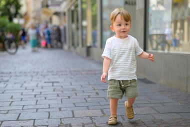 Sevimli genç bir çocuk şehir merkezindeki kaldırımlı yaya caddesinde güvenle yürüyor..