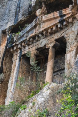 Turistler, Türkiye 'nin Akdeniz kıyısındaki Lycian nekropollerinin en dikkat çekici örneklerinden biri olan dev kaya mezarına hayran..