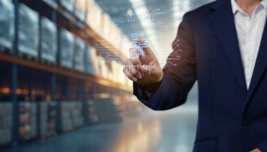 Bir iş adamı, modern tedarik zinciri yönetimi ve teknoloji entegrasyonunu vurgulayan bir depo ortamında dijital lojistik simgeleriyle etkileşime girer.