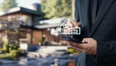 Bir işadamı gayrimenkul teknolojisiyle ilgilenmek için akıllı telefon kullanıyor, kentsel bir ortamda mülk alıp satmak için modern yöntemleri vurguluyor.