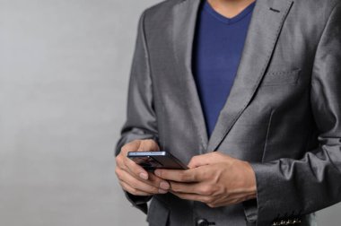Parlak takım elbiseli profesyonel bir adam akıllı telefonuna odaklanır, modern ve şık bir çevrede teknolojiyle işi harmanlar..