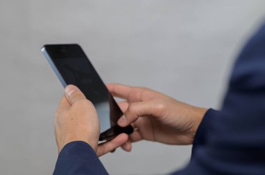Profesyonel bir ortamda akıllı telefon kullanan ellerin yakın plan görüntüsü, günlük yaşamda modern iletişim ve teknoloji kullanımını vurguluyor.