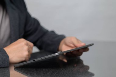 Modern bir tableti şık bir ofis ortamında tutan birinin yakın çekimi. Sahne, teknolojiyle odaklanmış bir etkileşim anını yakalıyor..