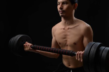 Odaklanmış bir erkek atlet, egzersiz ve uygun teknikle spor ve sağlığa kendini adamış olarak, ağır ağırlıklarla güç antrenmanı yapar..