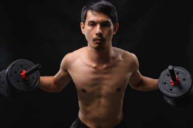 Kararlı bir adam dambılları odaklanarak kaldırır, gücünü gösterir ve spor yapmaya bağlılığını gösterir. Stok resimlerindeki sağlık, egzersiz ve kişisel büyüme temaları için ideal.