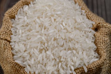 Doğal bir çuval içinde sergilenen taze toplanmış beyaz pirincin yakın plan görüntüsü. Bu resim, bu temel tahılın dokusunu ve kalitesini gösteriyor. Yemek ve sağlıklı yemekler için mükemmel..