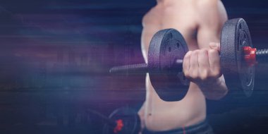 Canlı bir spor salonundaki dambılları kullanarak kas gücünü arttıran odaklanmış bir birey. Spor yapmak ve ilham almak için mükemmel..