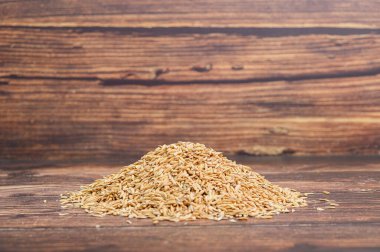 Kırsal ahşap bir zemindeki ham kimyon tohumlarının yakın çekim görüntüsü. Mutfak ve sağlıkla ilgili bağlamlar için ideal, doğal malzemelerin sergilenmesi.