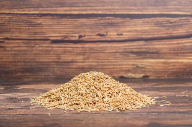 Kırsal ahşap bir zemindeki ham kimyon tohumlarının yakın çekim görüntüsü. Mutfak ve sağlıkla ilgili bağlamlar için ideal, doğal malzemelerin sergilenmesi.