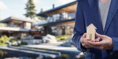 Minyatür bir ev tutan profesyonel bir birey, emlak alım, satım veya konut kiralama gibi emlak işlemlerinin dinamiklerini sembolize eder..