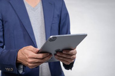 Akıllı günlük giysiler içindeki bir işadamı modern bir iç mekan ortamında günlük hayatta profesyonellik ve teknolojinin bir karışımını sergileyen bir tablet tutuyor..
