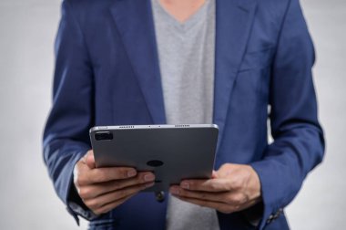 Modern teknoloji ve profesyonelliği yansıtan bir tablet taşıyan şık giyinmiş bir iş adamı. Çağdaş kurumsal hayatın özünü yansıtıyor..