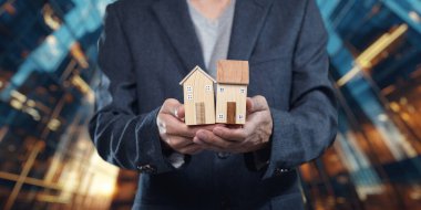 Bir iş adamı emlak satışlarını sembolize eden, emlak piyasasındaki yatırım fırsatlarını yansıtan iki model ev bulundurur. İş kavramları için mükemmel.