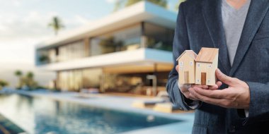 Profesyonel bir birey, çarpıcı lüks bir evin yanında, gayrimenkul satışları, iş stratejisi ve modern tasarım unsurlarının sergilendiği model evler sunar..