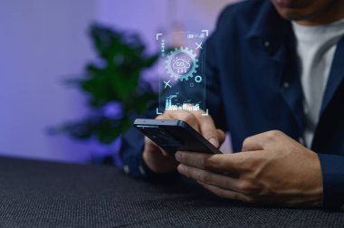 Ekranda gösterilen dijital veri analizi ile etkileşime geçmek için akıllı telefon kullanan bir kişi, yenilikçi teknoloji ve araştırmalar için modern çözümler sergiliyor.