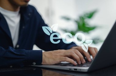 Modern bir çalışma alanında dizüstü bilgisayar kullanarak çevre dostu enerji çözümlerine odaklanmış bir profesyonel. Bu görüntü günlük uygulamalarda yenilik ve sürdürülebilirliği temsil etmektedir..