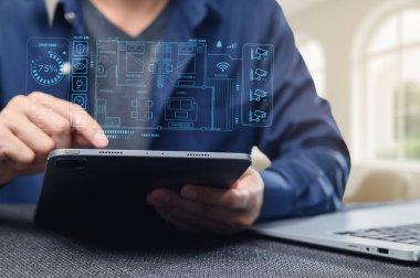 Bir kişi akıllı ev kontrolleri ve otomasyon özelliklerini gösteren bir tabletle etkileşime girer. Görüntü, teknolojinin modern yaşam ve kolaylıktaki rolünü yakalıyor..
