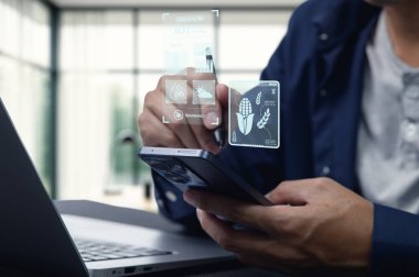 Modern ofis ortamında dijital tarımsal verileri gösteren akıllı bir telefonla meşgul olan kişi, teknolojinin tarım analizi ve sezgilerindeki rolünü vurguluyor.