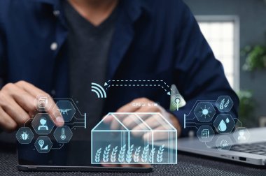 Bir kişi akıllı tarım teknolojisiyle etkileşim kurmak için akıllı telefon kullanır, sürdürülebilir tarım ve verimli kaynak yönetimi için modern çözümler sunar.