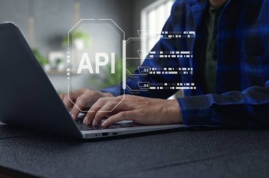 Bir iş adamı, API arayüzü grafik kaplamalı bir dizüstü bilgisayarla programlama yapıyor. Bu dijital çalışma alanı modern yazılım geliştirme ve teknoloji eğilimlerini yansıtır.