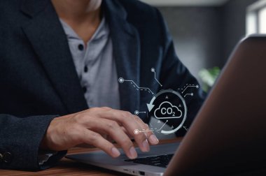 Bilgisayar klavyesinde CO2 emisyon grafik kaplamalı bir el yazısının yakından görüntüsü, teknolojinin çevresel veri analizindeki rolünü temsil ediyor..