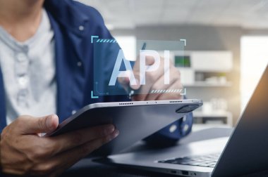 Bir programcı bir tablet ve dizüstü bilgisayar kullanarak API arayüzü geliştirmeye çalışır. Bu resim modern teknoloji ve yazılım yeniliğinin özünü yakalar..