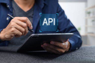 Bir geliştirici bir uygulama programlama arayüzü oluşturmak ve yönetmek için bir tablet kullanır. Sahne modern bir çalışma alanı yakalıyor, teknoloji ve yaratıcılık sergiliyor..