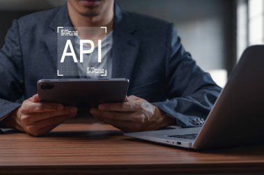 Bilgisayarla tamamlanmış API kaplamalı tablet kullanan birini gösteren profesyonel bir ayar. Bu görüntü modern programlamanın ve teknolojik bütünleşmenin özünü yakalar..