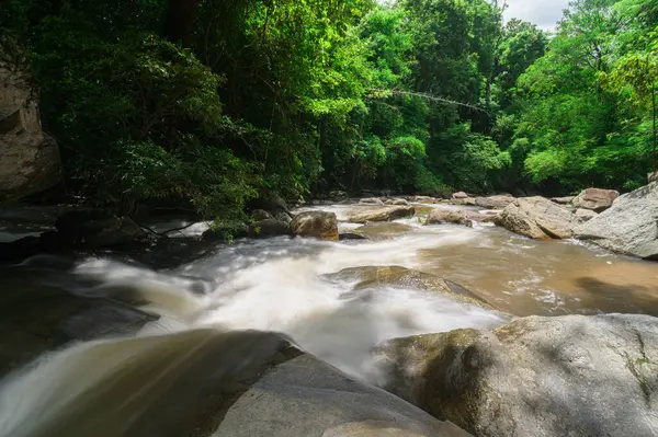 Chiang Mai 'de dingin bir şelalenin huzurlu güzelliğini tecrübe edin, canlı yeşillikler ve doğal kayalarla çevrili, macera ve rahatlama için mükemmel..