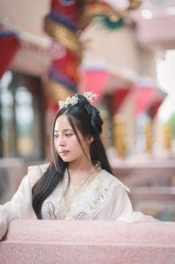 Geleneksel Çin kültürünü sergileyen, güzel bir el işi giyen genç bir kadın. Zarif saç stili ve sakin ifadesi, kültürel portreler için mükemmel sakin bir atmosfer yaratıyor..