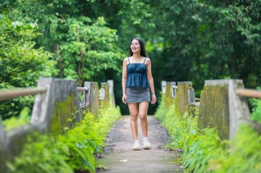 Bir kadın, canlı yeşil bir ormanda huzurlu bir şekilde dolaşmaktan zevk alır, doğanın güzelliğini ve sükunetini kucaklayarak, sakin bir açık hava ortamında.