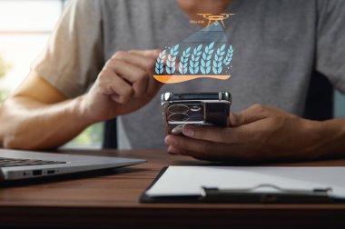 Yenilikçi teknolojiyle akıllı çiftçiliğin geleceğini keşfedin. Bu resim verimli tarım uygulamaları için akıllı aygıtlarla etkileşen bir kullanıcıyı gösterir.