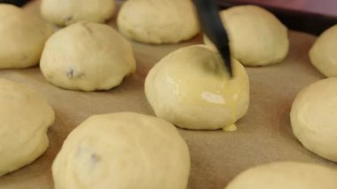 Pişirmeden önce üzümlü çörekleri yumurta ve sütle fırçalamak