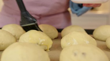 Pişirmeden önce üzümlü çörekleri yumurta ve sütle fırçalamak