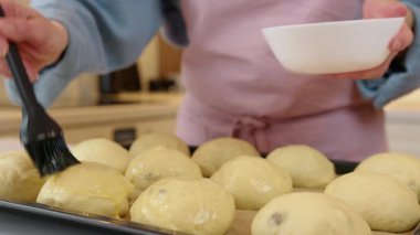 Pişirmeden önce üzümlü çörekleri yumurta ve sütle fırçalamak