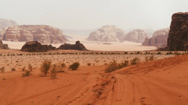 Wadi Rum Çölü 'nün görkemli manzarası, Ürdün, Ay Vadisi. Turuncu kum, sis, bulutlar. Duvar kâğıdı. Dünya simgeleri. Toprağın güzelliğini keşfedin. Ulusal park açık hava manzarası.